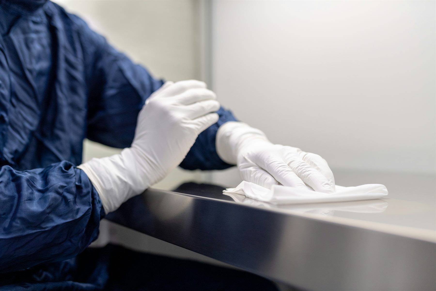 Gloved hands carefully wiping a surface